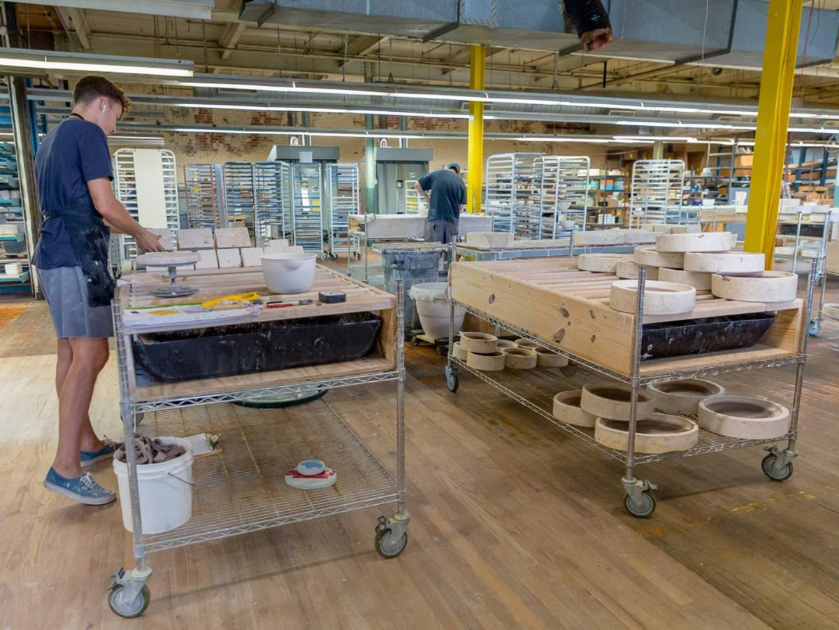 Several employees, workstations and products scattered across the production area of the studio.